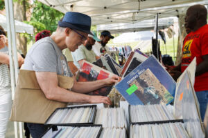 a man is looking through vinyl records at a vendor's table