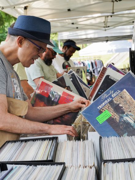a man is looking through vinyl records at a vendor's table