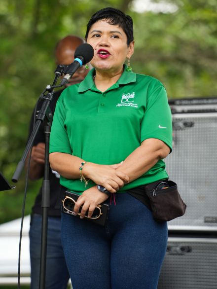 a woman in a green shirt is speaking into a microphone